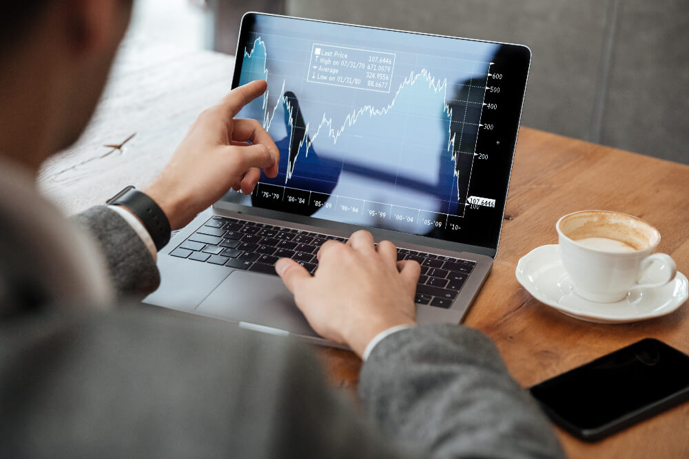 businessman-sitting-by-table-cafe-analyzing-indicators-of-stock-market-using-laptop