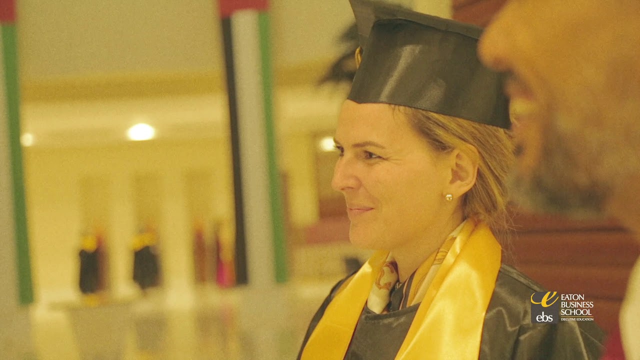 A woman in a graduation gown smiles at a man.