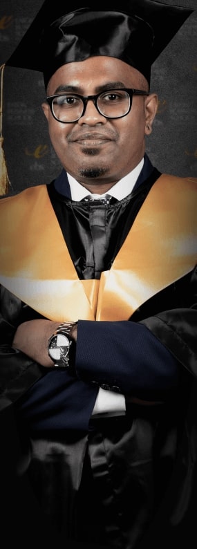A man in a graduation gown with his arms crossed.
