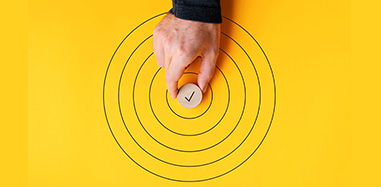 A person is touching a circle on a yellow background while pursuing an International MBA.